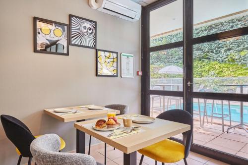 a dining room with a table and chairs and a window at Appart Hotel Odalys City Aix en Provence Les Floridianes in Aix-en-Provence