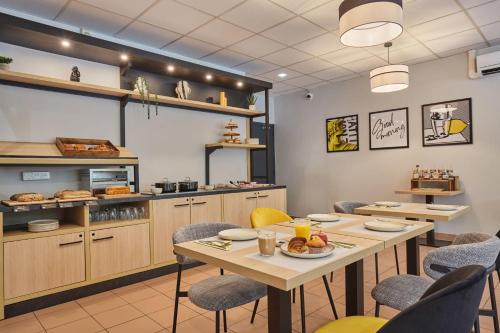 a restaurant with a table and chairs and a kitchen at Appart Hotel Odalys City Aix en Provence Les Floridianes in Aix-en-Provence