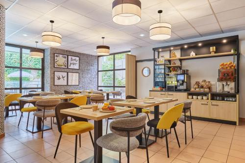 a restaurant with tables and chairs and a counter at Appart Hotel Odalys City Aix en Provence Les Floridianes in Aix-en-Provence