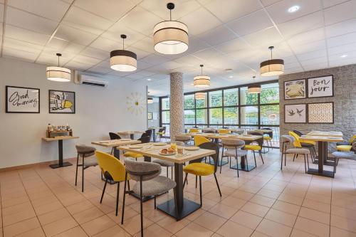 a restaurant with tables and chairs and windows at Appart Hotel Odalys City Aix en Provence Les Floridianes in Aix-en-Provence