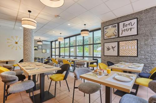 a restaurant with tables and chairs and windows at Appart Hotel Odalys City Aix en Provence Les Floridianes in Aix-en-Provence