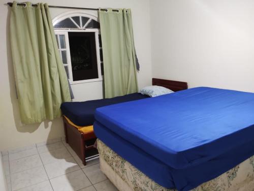 a bedroom with a blue bed and a window at Casa Faé in Guarapari