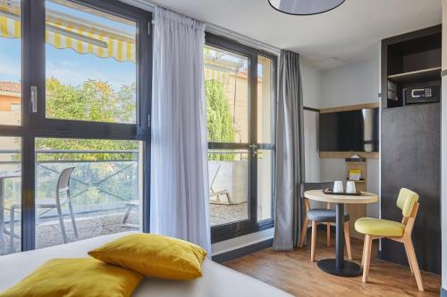 a hotel room with a bed and a table and a window at Appart Hotel Odalys City Aix en Provence Les Floridianes in Aix-en-Provence