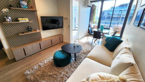 a living room with a couch and a tv at Resort-style Exec 1 Bed with study in Port Melbourne in Melbourne