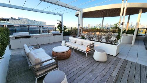 a rooftop patio with white furniture and a view of the city at Resort-style Exec 1 Bed with study in Port Melbourne in Melbourne