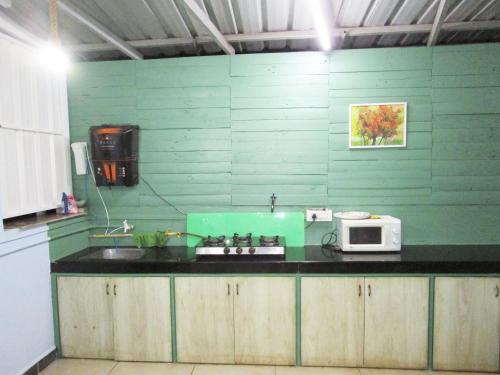 a green kitchen with a microwave on a counter at Private 1 BHK in a Penthouse with Living Space in Belgaum