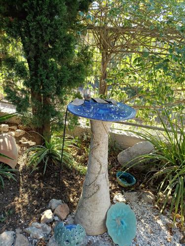 a blue bird bath sitting in a garden at Art Apartments in Midrakh ‘Oz