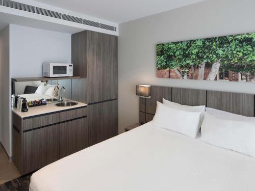 a hotel room with a bed and a microwave at Mercure Sydney Blacktown in Blacktown