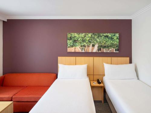 a room with two beds and a couch at Mercure Sydney Blacktown in Blacktown