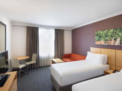 a hotel room with a bed and a desk at Mercure Sydney Blacktown in Blacktown
