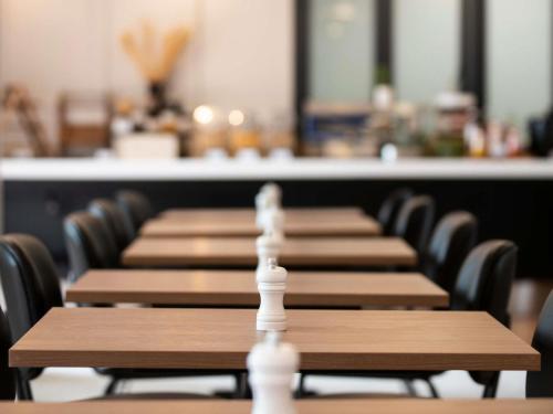 a row of wooden tables with chairs in a cafeteria at Mercure Sydney Blacktown in Blacktown
