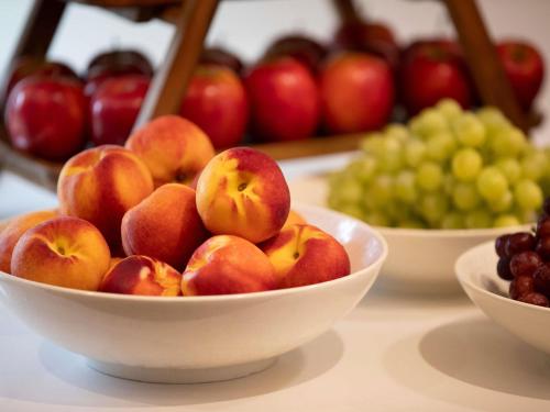 a group of bowls of apples and grapes on a table at Mercure Sydney Blacktown in Blacktown