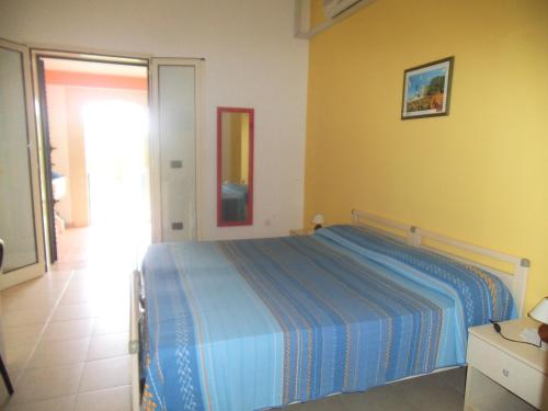 a bedroom with a blue bed and a yellow wall at Agriturismo L'Agrumeto in Otranto