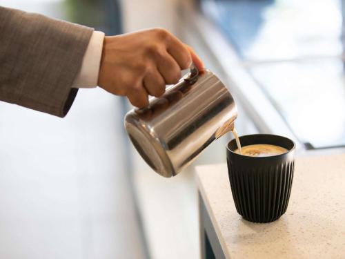 a person is pouring coffee into a cup at Mercure Sydney Macquarie Park in Sydney
