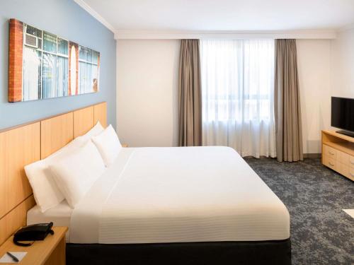 a hotel room with a bed and a television at Mercure Sydney Manly Warringah in Sydney