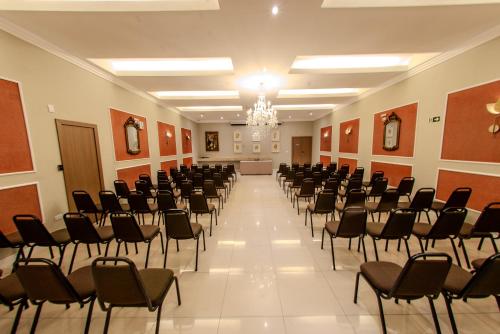 a large room with rows of chairs and a chandelier at Hotel Centro Europeu in Curitiba