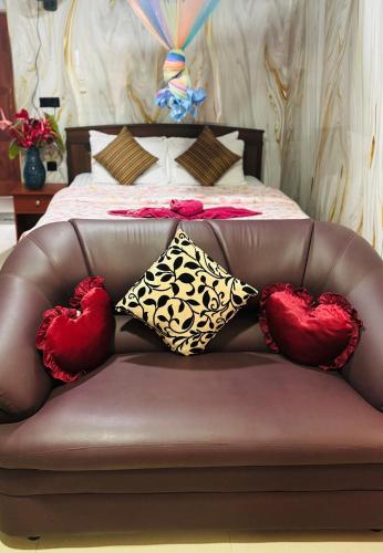 a brown couch with two hearts cushions on a bed at Grand adamspeak hotel & restaurant in Adams Peak