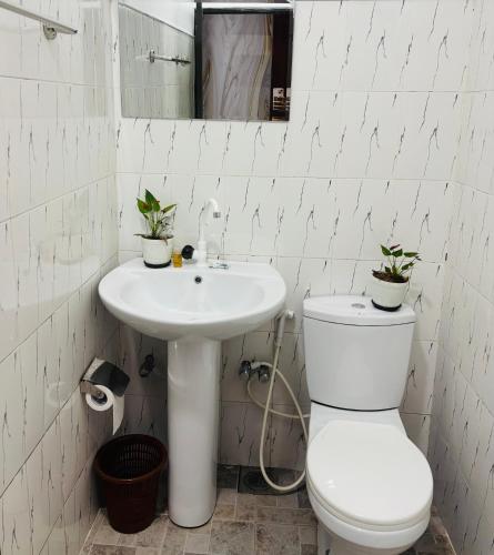 a white bathroom with a toilet and a sink at Grand adamspeak hotel & restaurant in Adams Peak