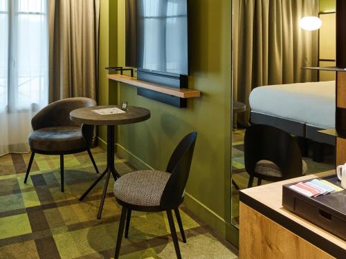 a hotel room with a bed and a table and chairs at Mercure Hôtel Le Touquet in Le Touquet-Paris-Plage