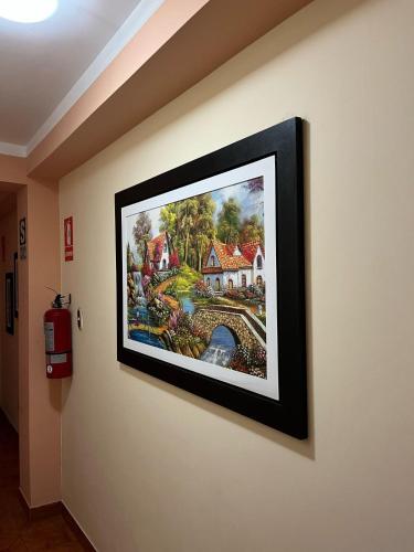 a framed painting of a house on a wall at lucero real hotel tacna 3 in Tacna