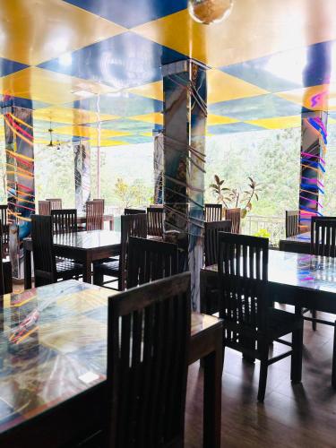 a restaurant with tables and chairs and a colorful wall at Grand adamspeak hotel & restaurant in Adams Peak