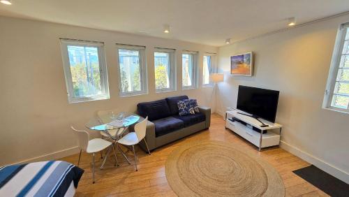a living room with a couch and a table and a tv at Spacious Studio Surrounded By Great Views in Sydney