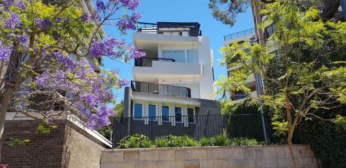 a white building with purple flowers in front of it at Spacious Studio Surrounded By Great Views in Sydney
