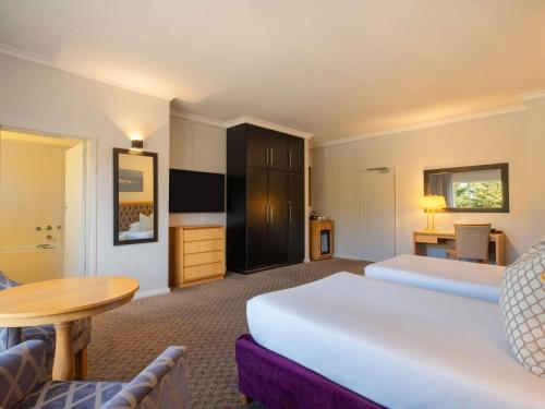 a hotel room with a large bed and a table at Mercure Hotel Windhoek in Windhoek
