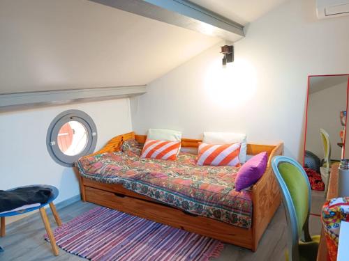 a bedroom with a bed with pillows and a window at La maison multicolore in Livron-sur-Drôme