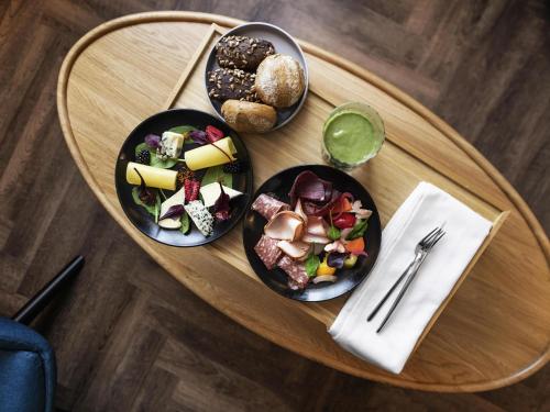 a wooden table with plates of food on it at MERCURE KLAIPEDA CITY HOTEL, Meetings, Events, Restaurant & Bar - Accor Group, Pet Stay FREE in Klaipėda