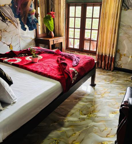 a bedroom with a bed with a red blanket on it at Grand adamspeak hotel & restaurant in Adams Peak