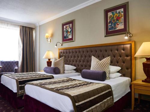 a hotel room with two beds in a room at Mövenpick Hotel Windhoek in Windhoek