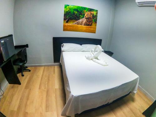 une chambre avec un lit blanc avec un tableau sur le mur dans l'établissement Madu Boutique Hotel, à Tefé