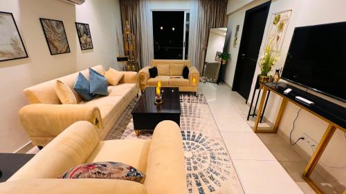 a living room with couches and a flat screen tv at Penta Square Signature Apartments DHA Phase 5 Lahore in Lahore