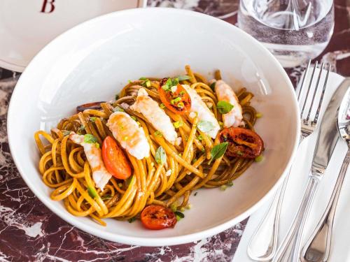 a white bowl of pasta with shrimp and vegetables at SO/ Paris Hotel in Paris