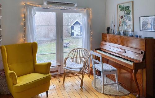 a living room with a piano and a chair at Cozy Home In Vejby With Wifi in Rågeleje