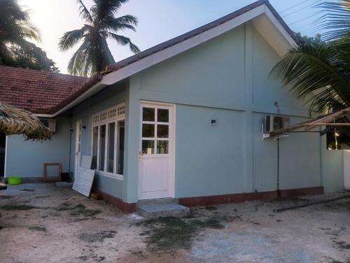a white building with a door and a palm tree at Delft Samudra Hotel in Jaffna