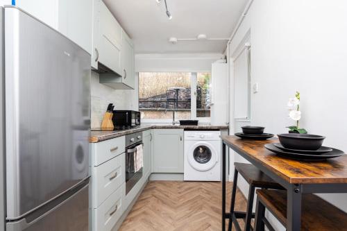 a kitchen with white cabinets and a wooden table at 2 Bedroom House - Free Parking in Annan