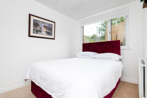 a white bedroom with a large bed and a window at 2 Bedroom House - Free Parking in Annan