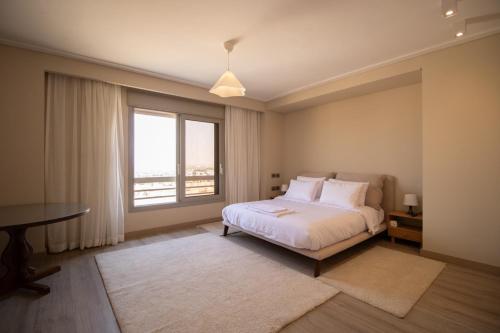 a bedroom with a bed and a window and a desk at Luxury Rooms in the Heart of Pyramids in Kafr Ghaţāţī