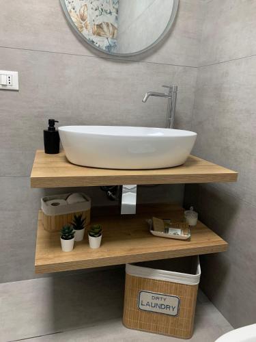 a white sink on a wooden shelf in a bathroom at Apa Sicula in Avola
