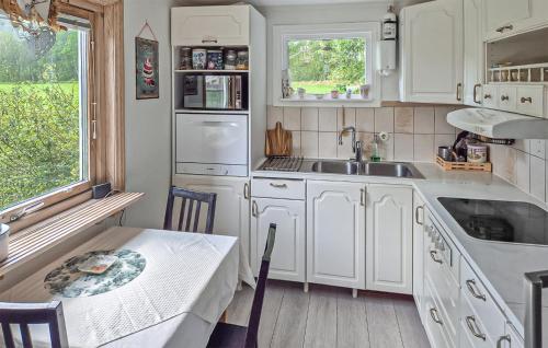 a kitchen with white cabinets and a table and a sink at Awesome Home In Hyssna in Hyssna