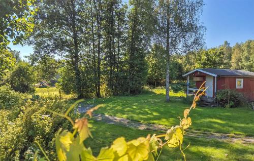 a garden with a red cabin in the background at Awesome Home In Hyssna in Hyssna