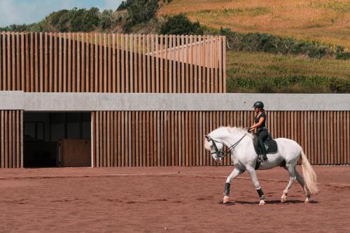 a person riding a white horse in front of a building at Lusitano Garden Villas in Ponta Delgada