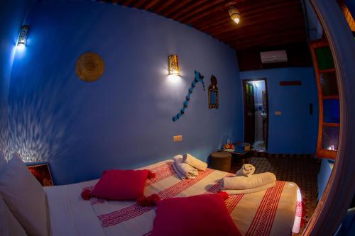 a bedroom with a blue wall and a bed with red pillows at Riad Misk Fez in Fès