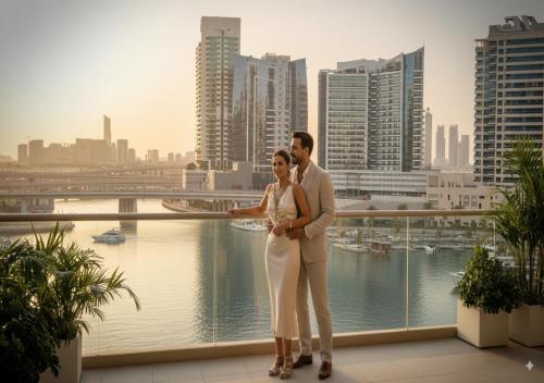 a man and a woman standing on a balcony with a city at Keyrock - Lake-View Apartment at Reva Residences, Business Bay with Pool, Gym & Free Parking in Dubai