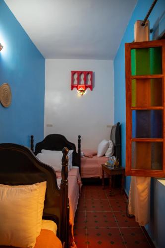 a bedroom with two beds and a blue wall at Riad Misk Fez in Fès