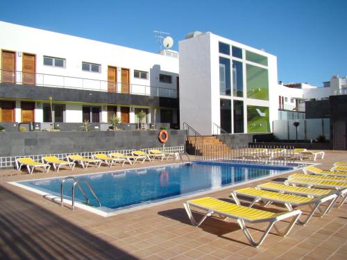 a swimming pool with lounge chairs next to a building at On the Beach in Corralejo