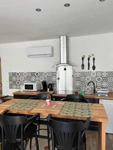 Gite d'Oliva في Suèvres: مطبخ مع طاولات خشبية وكراسي سوداء