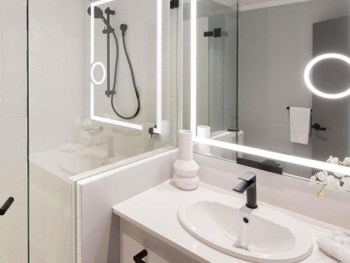 a white bathroom with a sink and a mirror at The Sebel Sydney Martin Place in Sydney